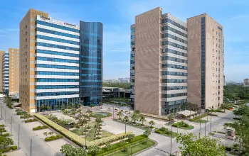 Twin modern office towers with glass facades, surrounded by landscaped green spaces and walkways.